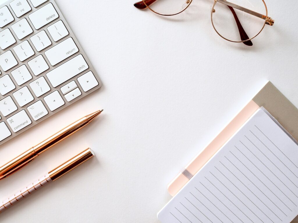 Desk with keyboard, notebook, and glasses